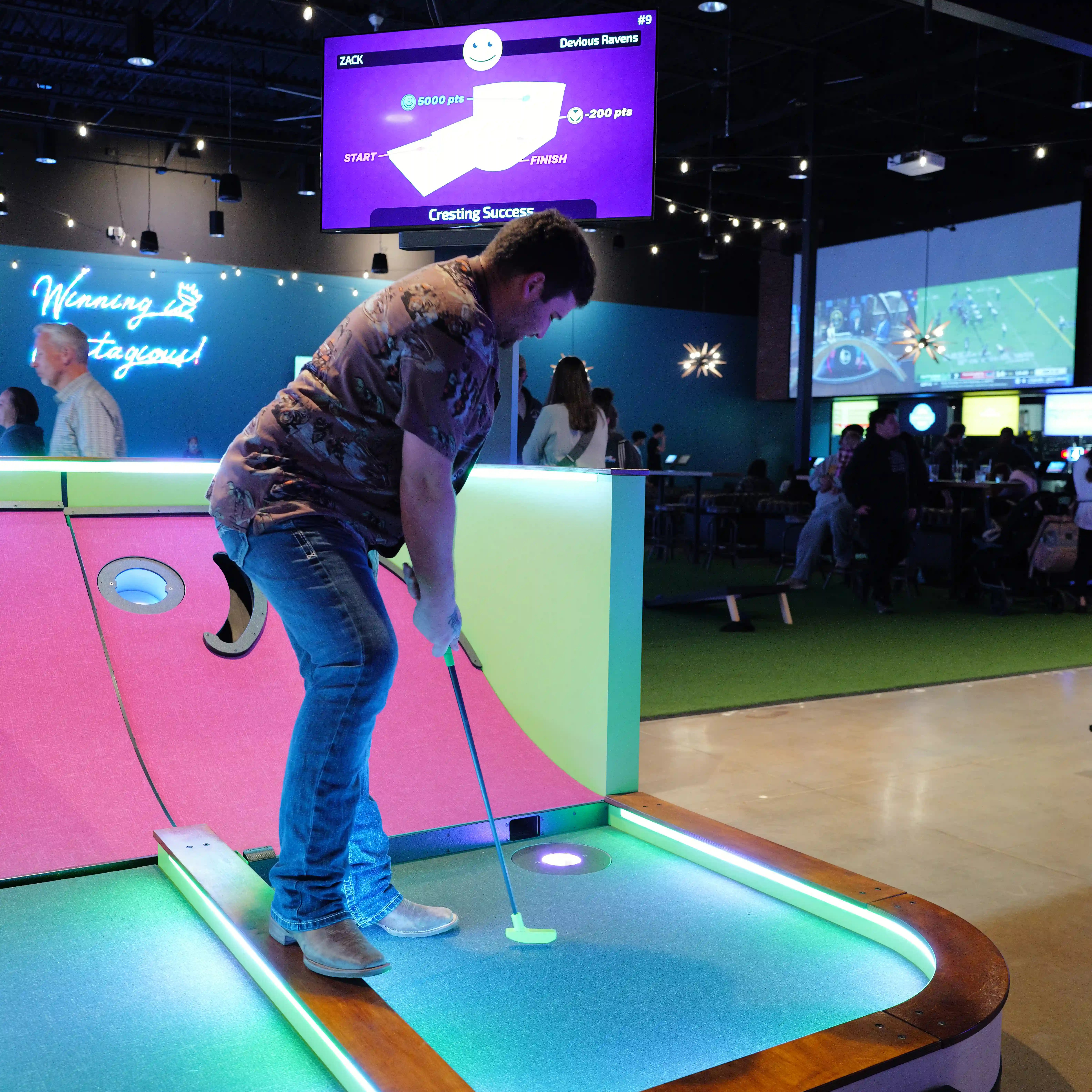 man putting at indoor mini golf course